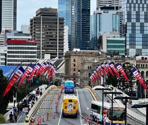 View of a Brisbane bridge with city buildings in the background flying Westpac branded Social Enterprise World Forum flags