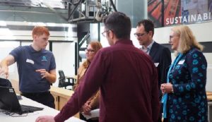 Australian Spatial Analytics employee stands in front of a computer explaining his work to a group of four onlookers including White Box Enterprises CEO Luke Terry
