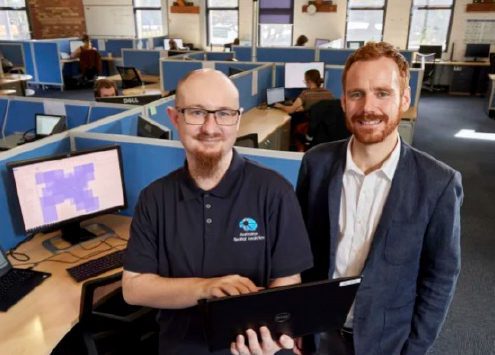 Two Australian Spatial Analytics employees standing in their office smiling