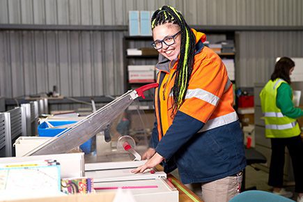 Green Collect employee smiling in high vis jacket using cutting tools