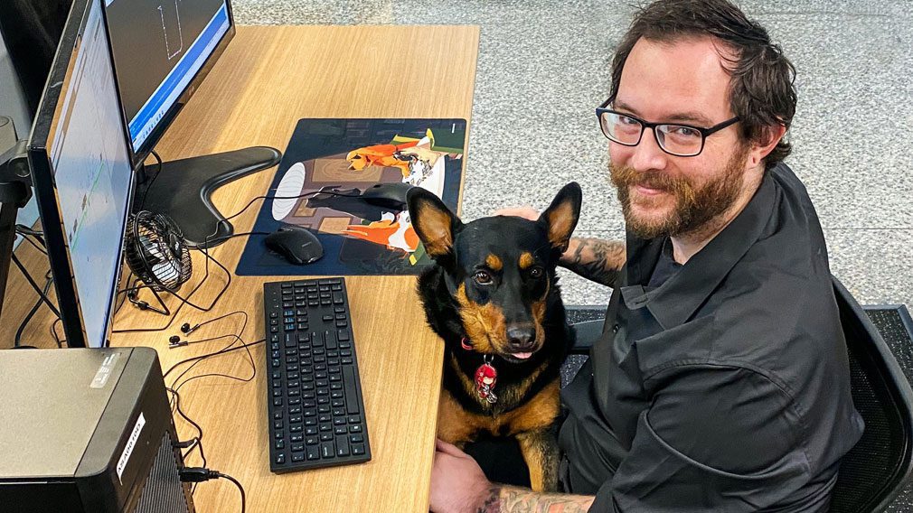 Australian Spatial Analytics employee, Nick, sitting in front of his computer with a dog on his lap
