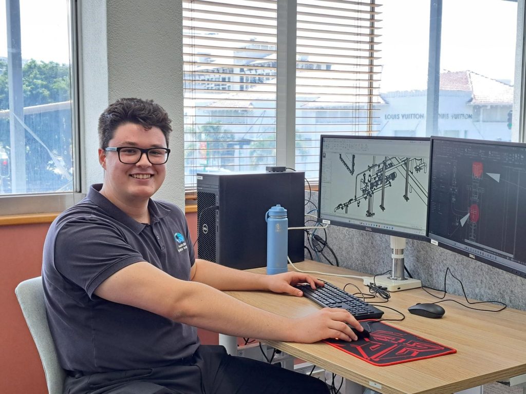 Australian Spatial Analytics employee sitting at a desk with computer in the Cairns office of ASA