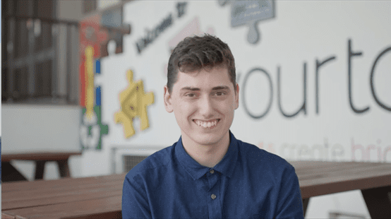 A young man named Kaleb sitting at a wooden table smiling