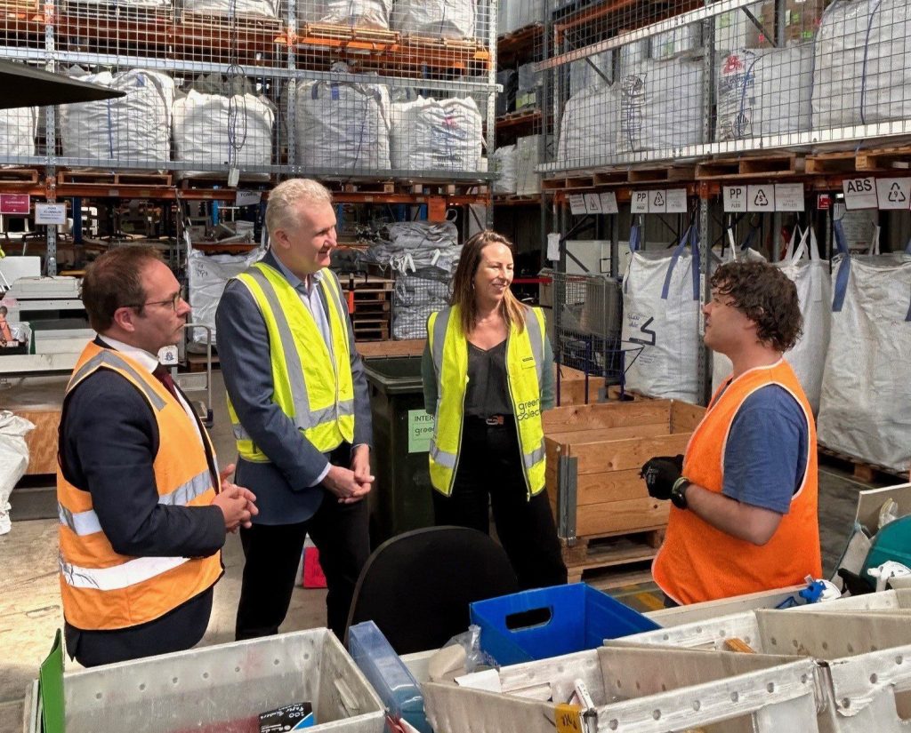 Federal Minister Tony Burke standing in a warehouse with Federal MP Daniel Mulino, Sally Quinn CEO of Green Collect, and another employee.