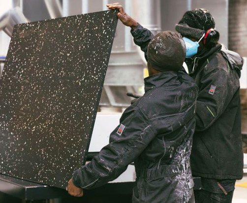 two people holding recycled plastic that repurposed into stadium seats,